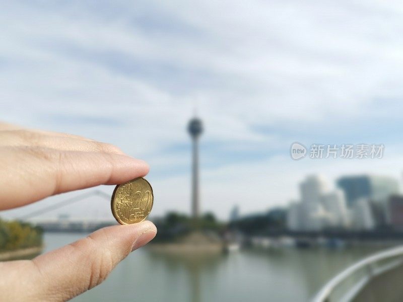 妇女手中的20分欧元硬币手指在背景Düsseldorf Medienhafen